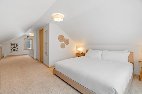 A cozy attic bedroom with a large bed and decorative elements reminiscent of nature.