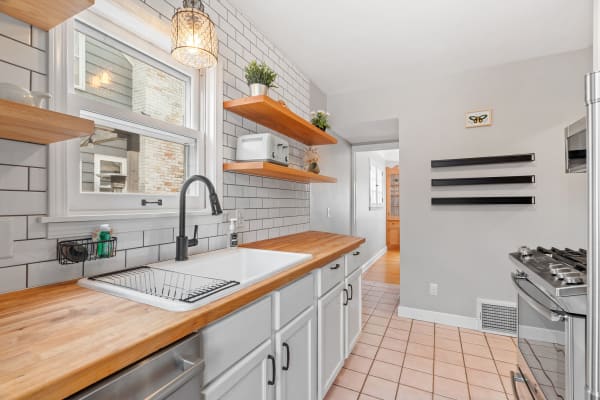 Modern kitchen featuring a white sink, black faucet, and wooden shelves.