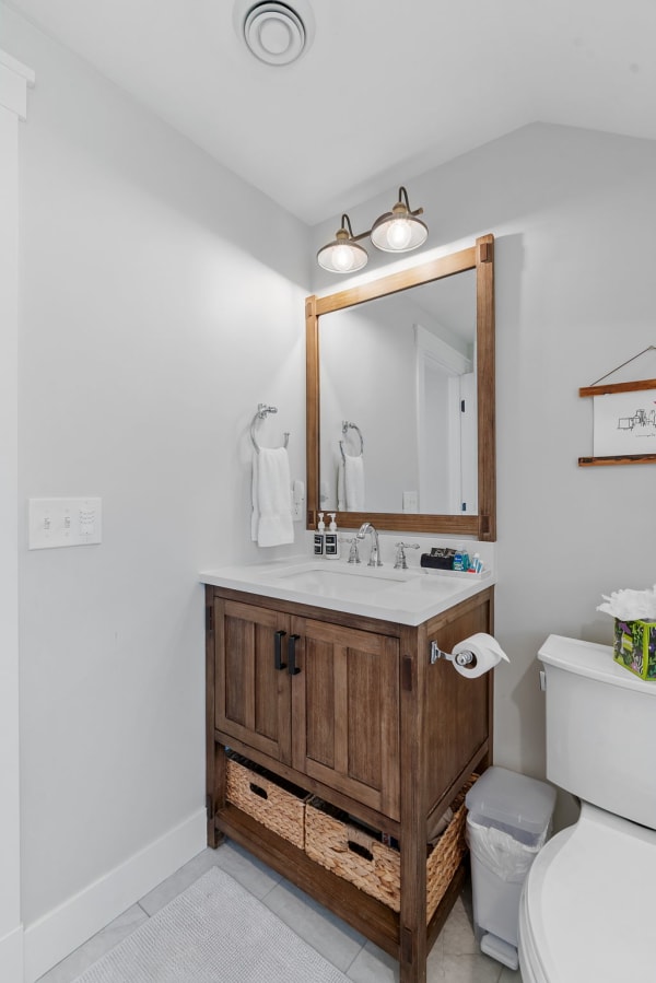 Modern bathroom with wooden vanity, two sinks, and pendant lighting.