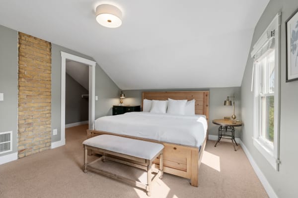 Inviting bedroom featuring a wooden bed, beige carpet, and natural light.