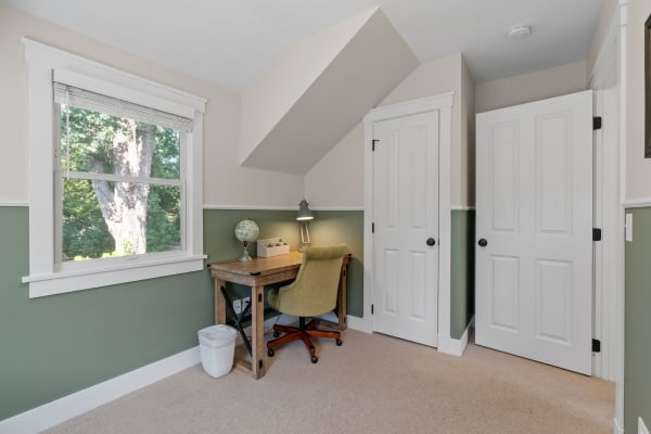 A home office featuring a wooden desk, chair, globe, and view of a tree outside.