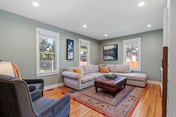 Cozy living room with light gray walls, a sectional couch with mustard pillows, and vibrant artwork.
