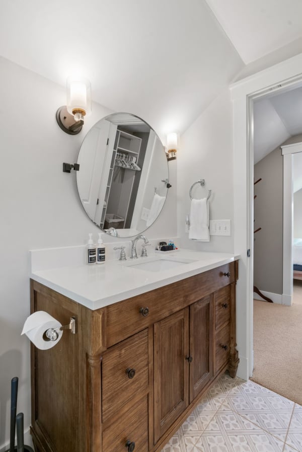 Contemporary bathroom with wooden vanity and round mirror