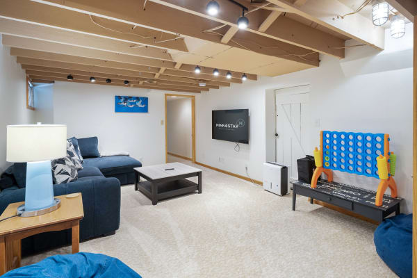 Cozy basement living area with a blue sectional sofa, coffee table, and connect-four game.