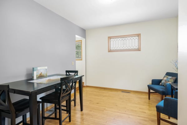 Cozy modern dining space featuring a black table, blue armchair, and hardwood flooring.