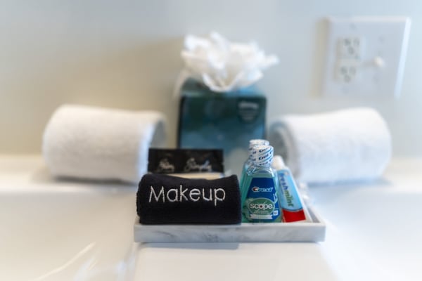 A bathroom countertop featuring a towel labeled 'Makeup', mouthwash, toothpaste, and neatly rolled towels.