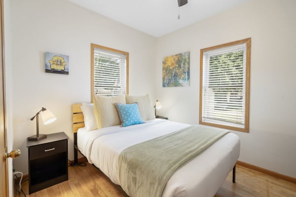 Cozy bedroom with a bed, nightstand, lamp, and artwork on the walls.