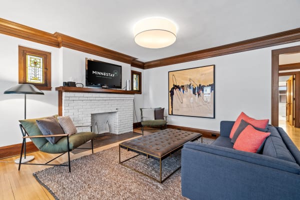 Stylish living room with navy sofa, abstract artwork, and a white brick fireplace.