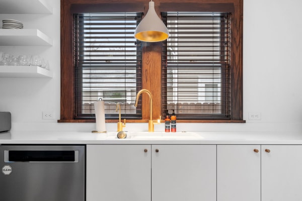 A contemporary kitchen area with a golden faucet and modern shelving.