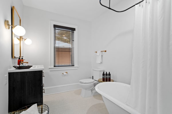 Modern bathroom with a white freestanding bathtub, sleek vanity, and minimalist decor.
