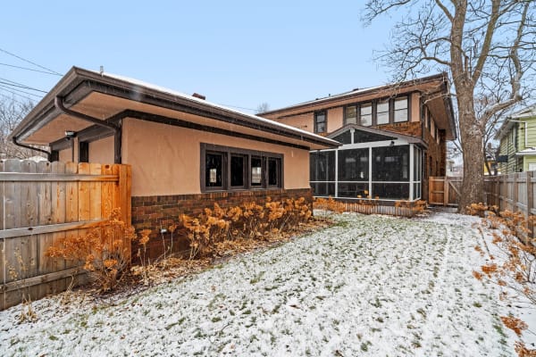 A home in winter with snow covering the lawn and dried plants in the garden.