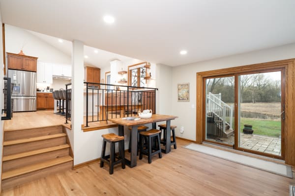 Interior view of a modern kitchen and dining area, featuring wooden cabinets and a sliding door to the outside.