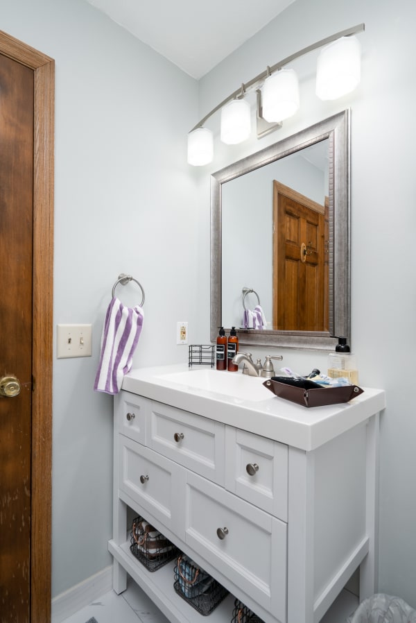 Modern bathroom with white vanity, silver mirror, and soft gray walls.
