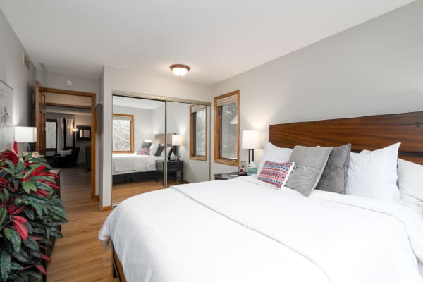 Inviting bedroom with a made bed, decorative pillows, and reflective mirror.