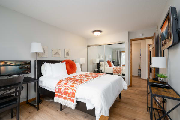 Cozy bedroom featuring a queen-sized bed, modern decor, and warm wooden flooring.