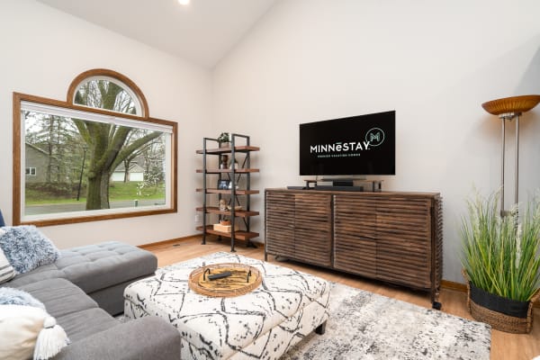 Cozy living room with a gray sectional couch, a wooden coffee table, and a shelf with decorative items.