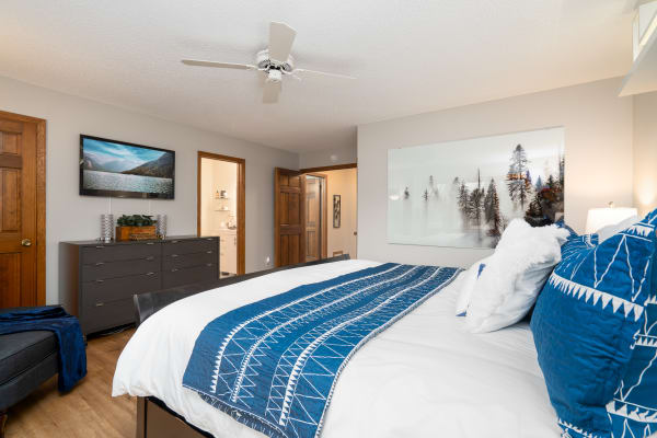 A modern bedroom featuring a large bed with blue and white bedding, a flat-screen TV, and decorative elements.