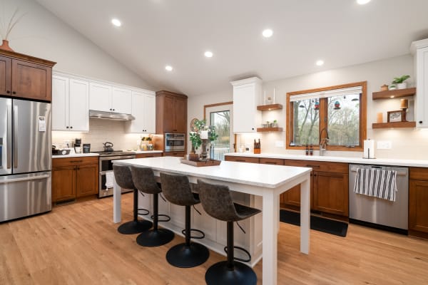 Modern kitchen with white and wood cabinetry, stainless steel appliances, and a central island.
