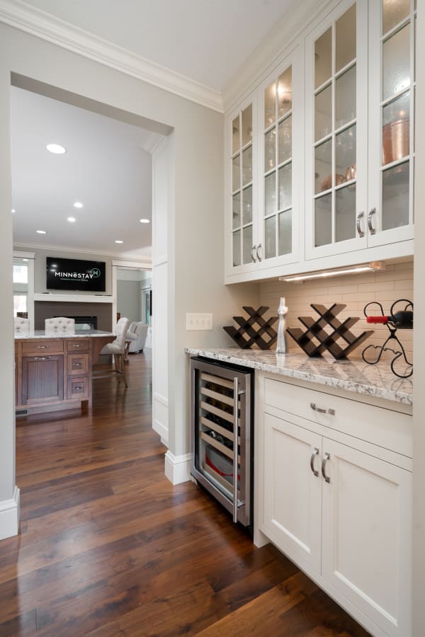 A corner of a modern kitchen featuring glass-fronted cabinets and a wine fridge.