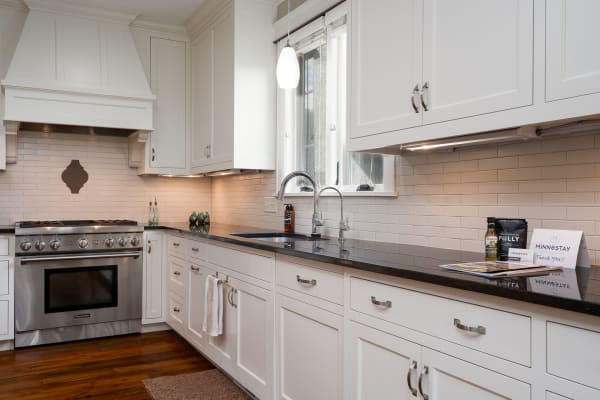 Modern kitchen with white cabinets and stainless steel appliances.
