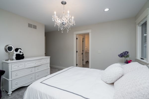 A beautifully designed bedroom featuring a white bed, dresser, and decorative elements.