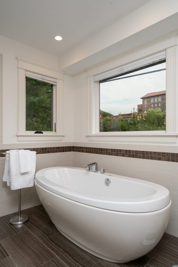 Modern bathroom with freestanding tub and windows.