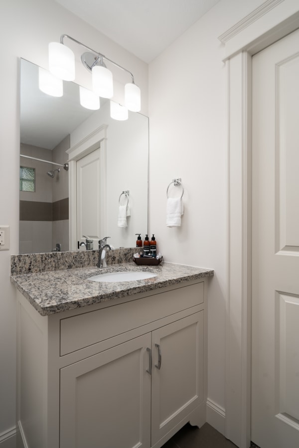 Modern bathroom with granite countertop and elegant lighting fixtures.