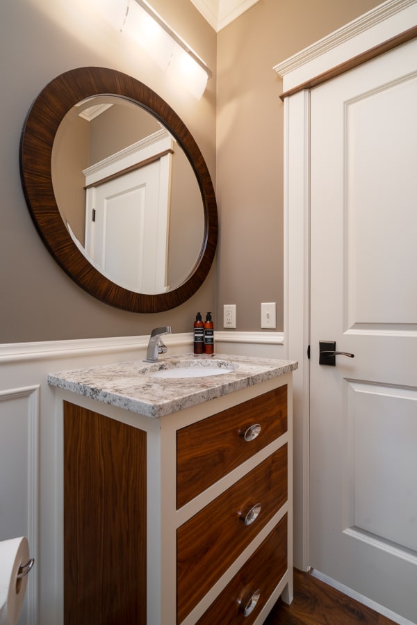 Modern bathroom with a round mirror and wooden vanity.