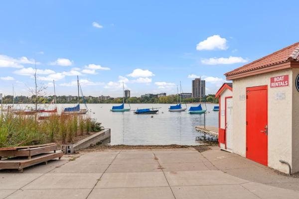 Lakeside view with colorfully covered sailboats and a boat rental shack.