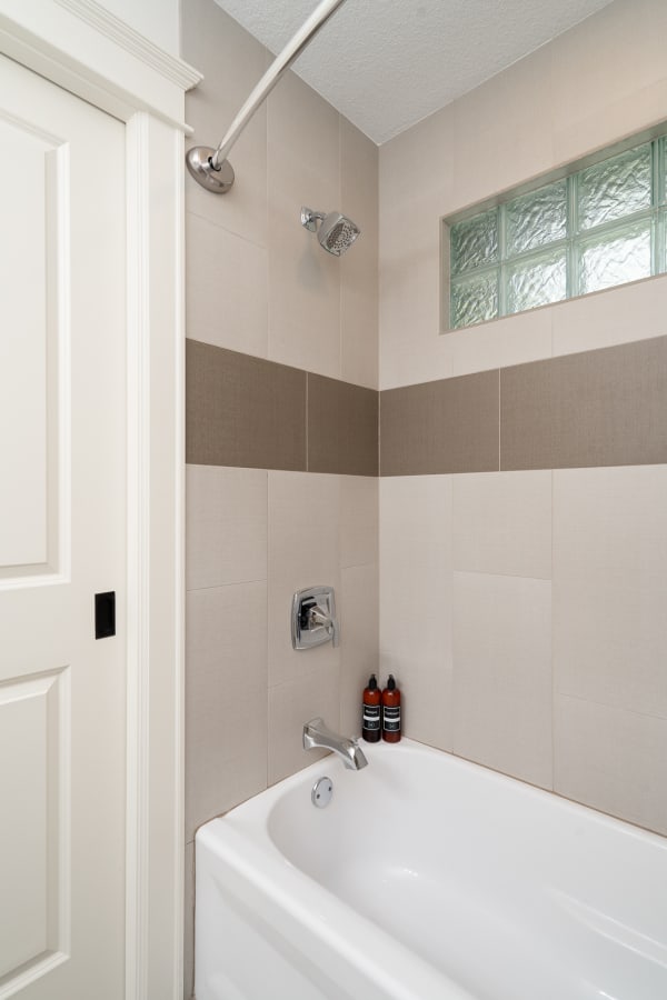 Modern bathroom corner with a white bathtub and chrome fixtures.