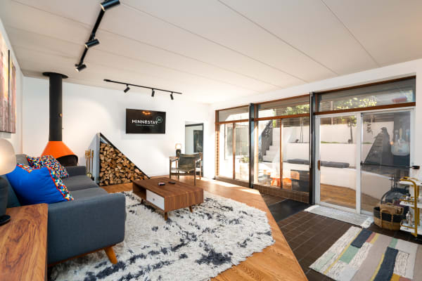 Modern living room featuring a gray sofa, colorful pillows, an orange fireplace, and large glass doors opening to an outdoor space.