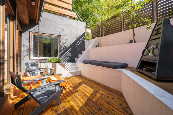 Stylish outdoor area featuring dark chairs, orange table, and lush greenery.