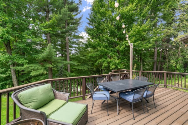 Outdoor deck with seating and dining area in a natural setting.