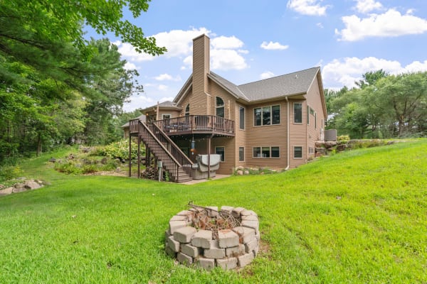 A beautiful two-story home with a wooden deck, set in a lush green backyard.