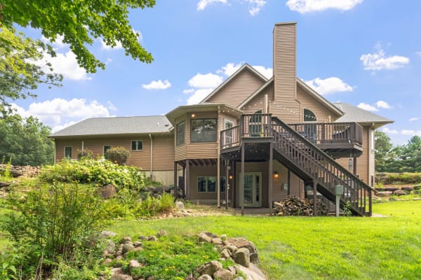 Exterior view of a two-story house with a garden and a wooden deck.
