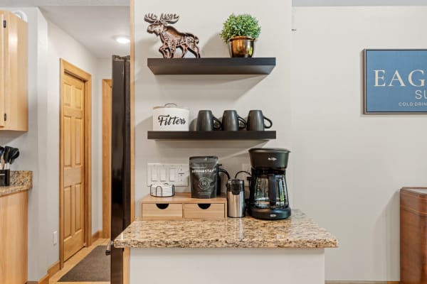 A kitchen countertop with coffee maker, mugs, and decorative items.