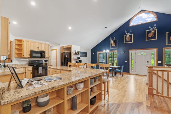 A spacious kitchen with wooden cabinets, dark appliances, and a dining area with blue walls and deer head decor.