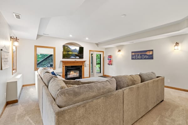 A well-decorated living room featuring a sectional sofa, fireplace, and TV with scenic view.