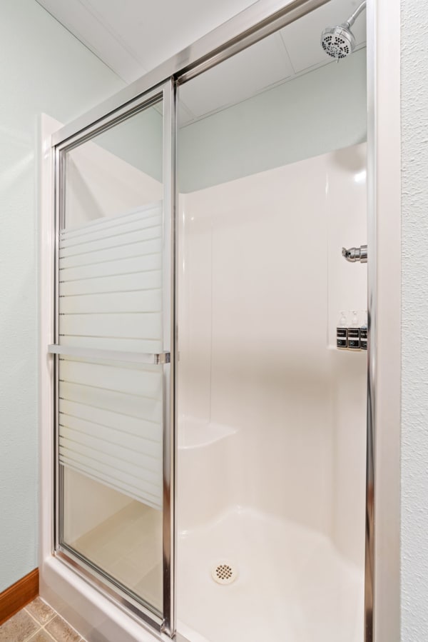 Interior view of a modern shower stall with glass doors and a built-in seat.