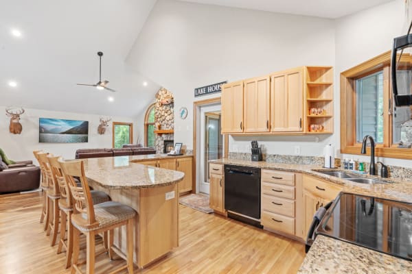 Spacious kitchen featuring light wood cabinetry, granite countertops, and rustic decorations.