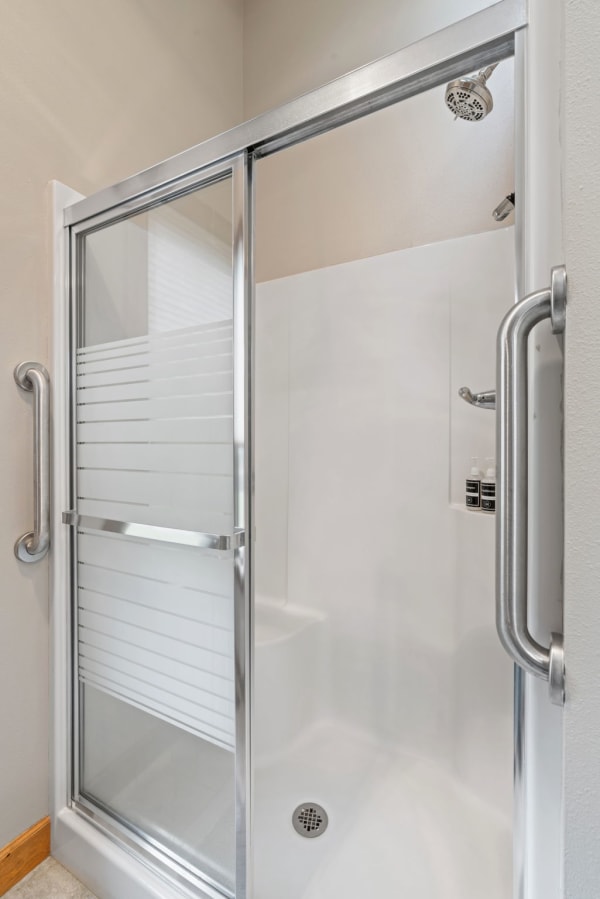 A modern shower with clear glass doors and a glossy white interior.