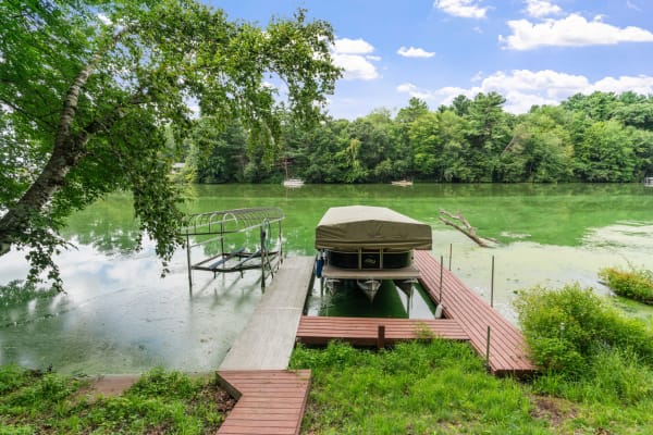 Serene lakeside view with a covered boat on a dock and lush surroundings.
