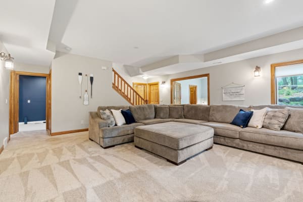 Spacious living room featuring a gray sectional sofa, decorative pillows, and light beige carpeting.