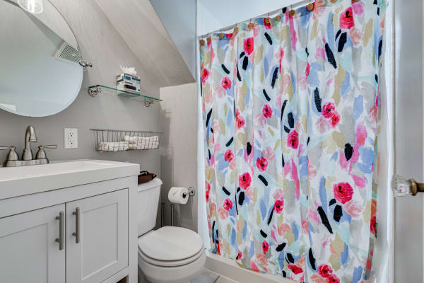 Modern bathroom featuring a floral shower curtain and sleek fixtures.