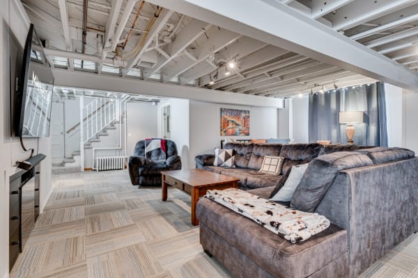 Cozy basement living room with large couches, a coffee table, and a mounted television.