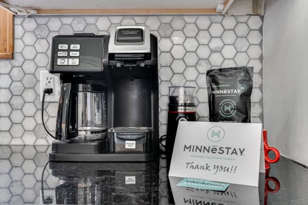 Coffee maker, coffee bag, and thank you note on a stylish black countertop.