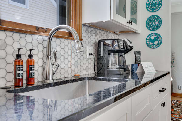 Contemporary kitchen with a stainless steel faucet, hexagon tile backsplash, and colorful decorative plates.