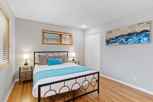 Interior view of a stylish bedroom featuring a metal bed frame, colorful pillows, and modern artwork.