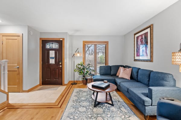 A living room featuring a blue sectional sofa, a coffee table, and decorative plants.
