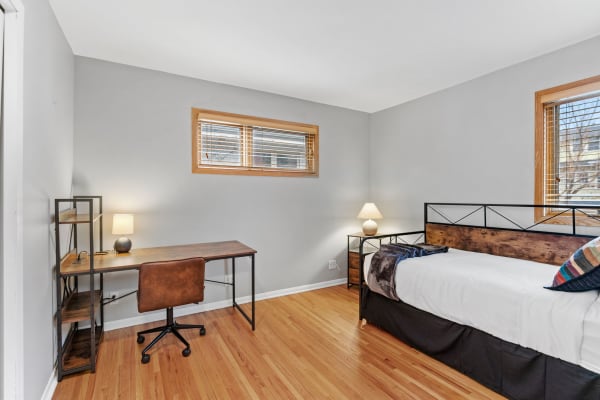 A modern bedroom with a bed, desk, and warm wood accents.